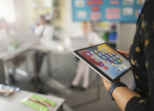 A Teacher Looking At Her IPad In The Classroom