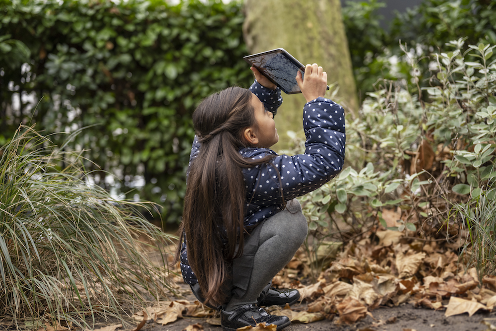 A girl using ipad to capture photos in a forest