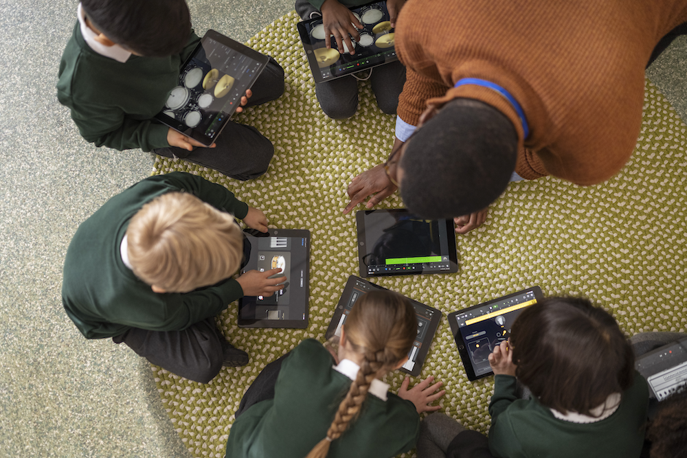 students and their teacher working on the floor creating music on ipad with Garage Band