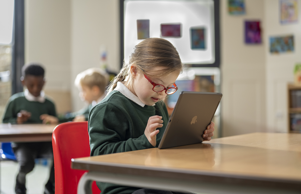 a girl with downs syndrome looking at an ipad in school