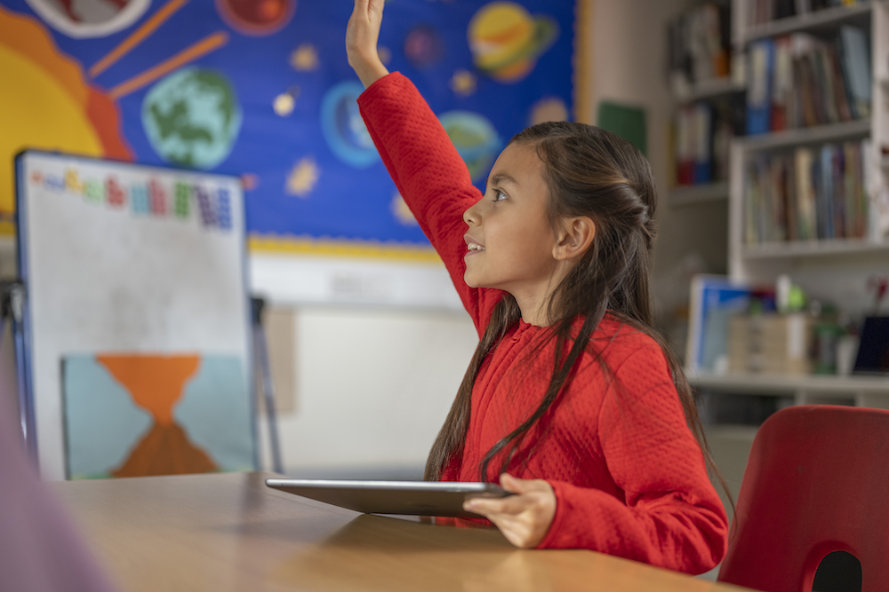 a female student raising her hand in class