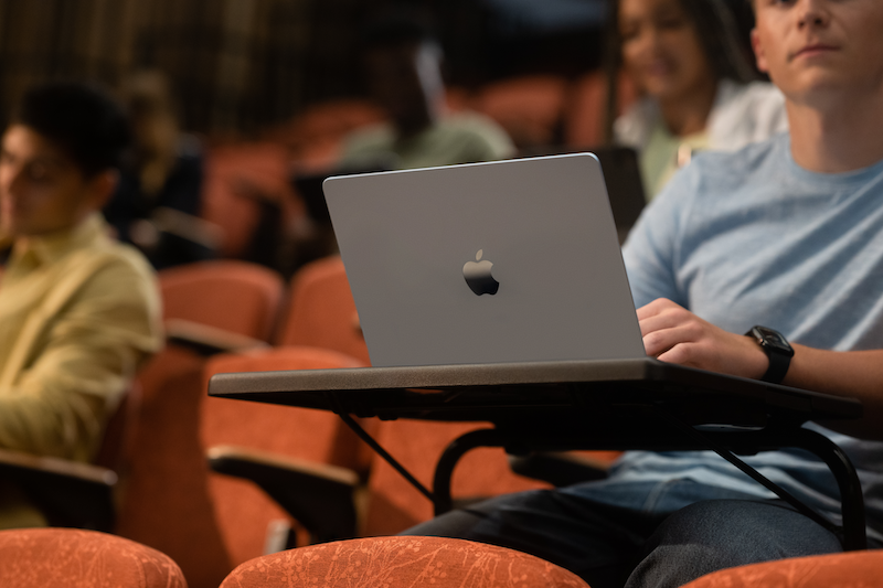 a student in a lecture hall with a macbook a student in a lecture hall with a macbook